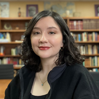 female with dark hair in front of bookcase